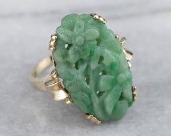 May include: A green jade ring with a carved floral design set in a gold band.