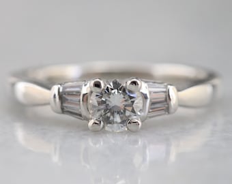 Anillo de compromiso de platino con diamante, talla brillante redonda, detalles baguette