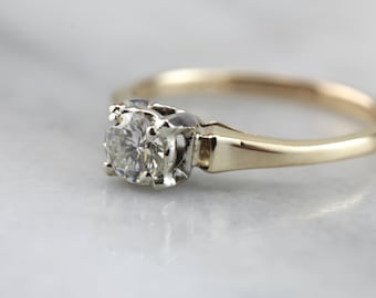 May include: A gold band engagement ring with a single round diamond set in a white metal prong setting.