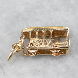 May include: Gold-tone charm of a San Francisco cable car. The charm has a detailed design and says "Cable Car" on the side.