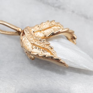 May include: A gold pendant featuring a white mother of pearl tooth set in a detailed gold leaf design.