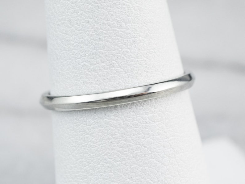 May include: A close-up of a silver wedding band with a smooth, polished finish.