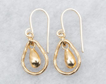 Pode incluir: Um par de brincos de ouro em forma de lágrima com um pequeno charme de lágrima pendurado dentro de cada lágrima maior.