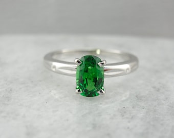 May include: A silver ring with a green oval gemstone set in a prong setting.