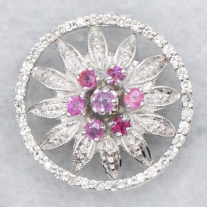 Ciondolo a forma di fiore con grappolo di rubini e diamanti e anello di aggancio nascosto.