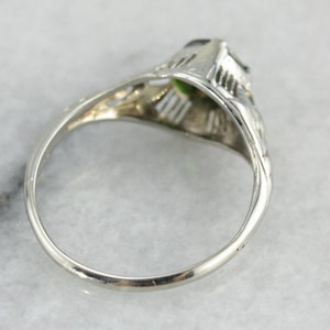 May include: A silver ring with a green gemstone set in a filigree design.