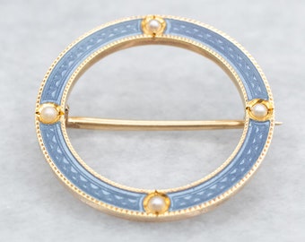 May include: A circular gold brooch with a blue enamel design and four white pearl accents.