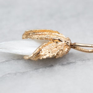 May include: A gold-tone pendant featuring a white mother-of-pearl flower with detailed leaf accents.