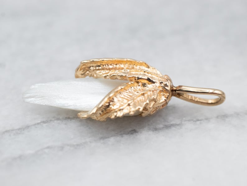May include: A gold-tone pendant featuring a white mother-of-pearl flower with detailed leaf accents.