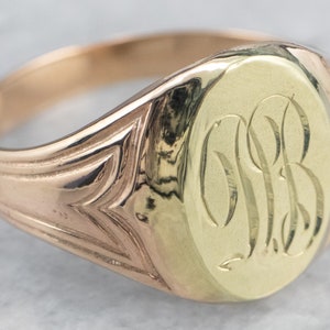 Könnte beinhalten: Ein goldener Siegelring mit einer ovalen Oberseite. Die Oberseite des Rings ist mit den Initialen "S.B." graviert.