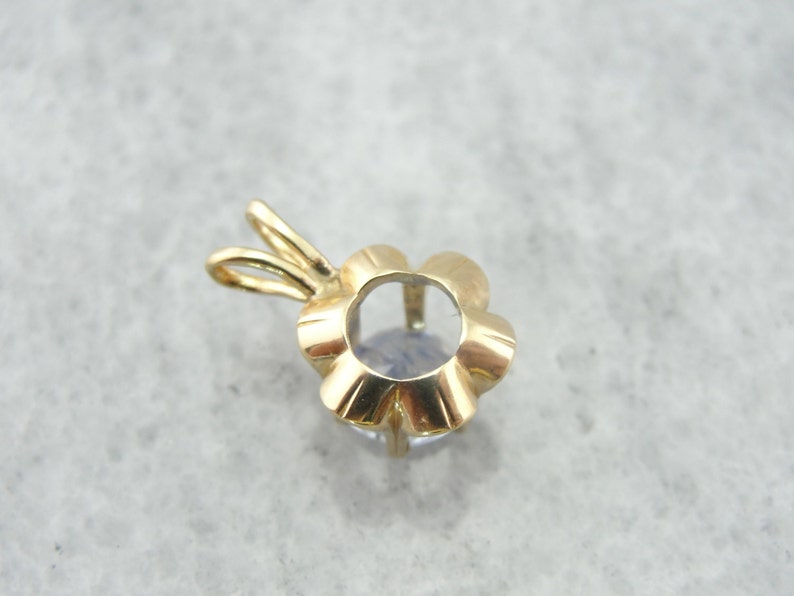 Op de afbeelding: Gouden hanger met een bloemvormige zetting voor een edelsteen. De zetting is leeg en klaar om met een steen te worden gevuld.