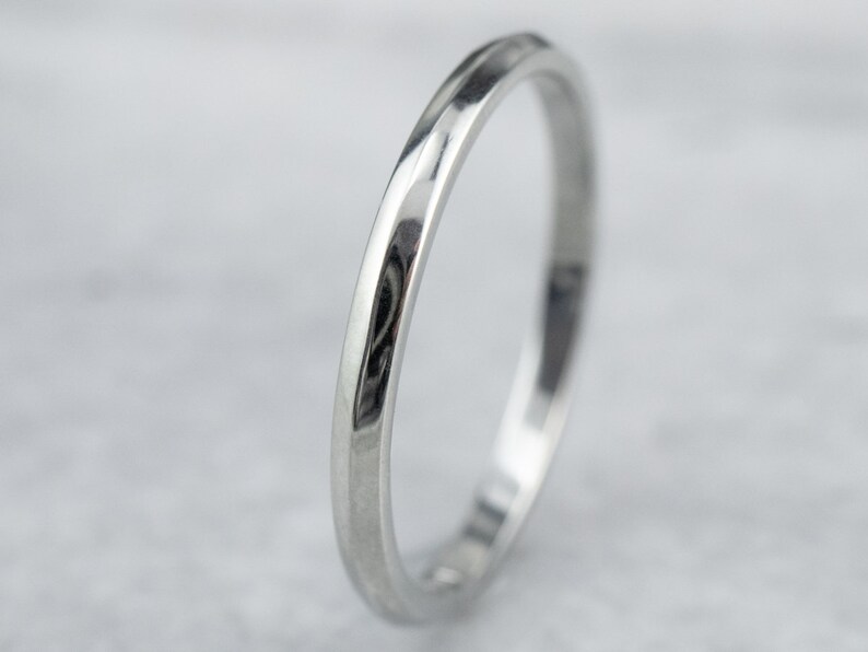 May include: A simple silver wedding band with a slightly rounded edge.