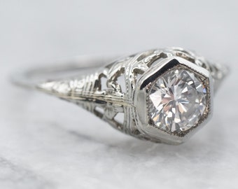May include: A vintage engagement ring with a delicate filigree design and a round brilliant cut diamond.