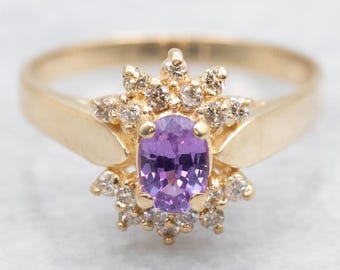 Anillo de oro amarillo de 14 quilates con zafiro rosa y halo de diamantes.