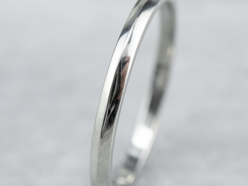 May include: A simple, polished silver wedding band with a slightly rounded edge.