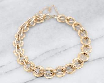 May include: A gold chain necklace with a unique, textured, circular link design.