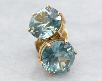 May include: A pair of gold stud earrings with round, faceted, light blue gemstones.