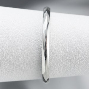 May include: A silver wedding band with a textured, diamond-cut finish.