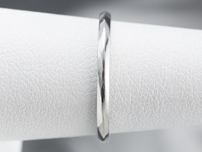 May include: A silver wedding band with a textured, diamond-cut finish.
