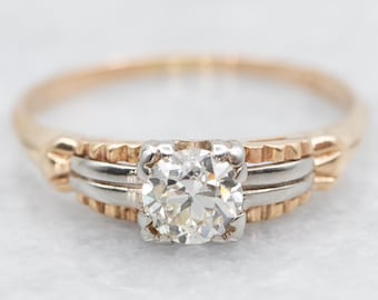 May include: A vintage engagement ring with a round brilliant cut diamond set in a two-tone gold band. The band is made of yellow gold and white gold, and the diamond is set in a prong setting.