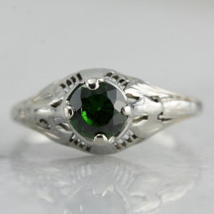 May include: A silver ring with a delicate filigree design and a round green gemstone.