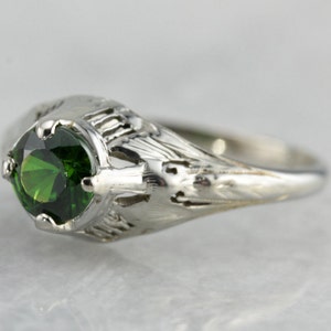 May include: A silver ring with a green gemstone set in a filigree design.