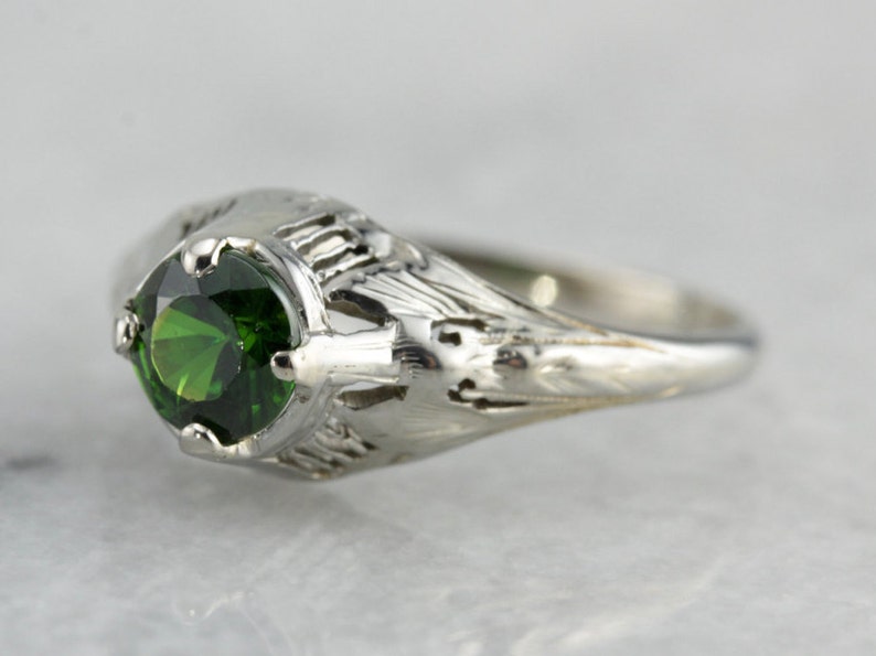 May include: A silver ring with a green gemstone set in a filigree design.