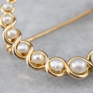 Puede incluir: Un broche de oro con un delicado dise&ntilde;o de perlas blancas dispuestas en espiral.