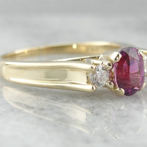 May include: A gold ring with a large oval ruby gemstone and two smaller round diamonds on either side.