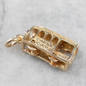 May include: Gold-toned charm of a San Francisco cable car with the words "Cable Car" inscribed on the side.