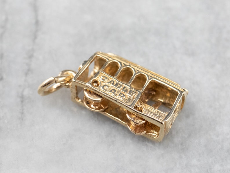 May include: Gold-toned charm of a San Francisco cable car with the words "Cable Car" inscribed on the side.