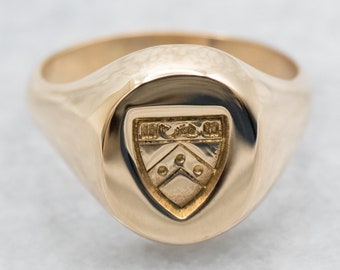 Könnte beinhalten: Ein goldener Siegelring mit einem Wappen, das einen Schild mit einem Chevron und drei Punkten zeigt.