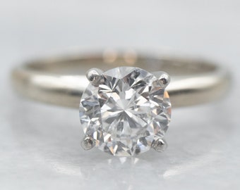 May include: A silver engagement ring with a large, round, clear diamond.
