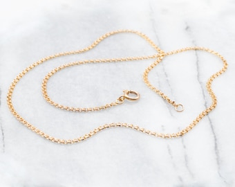 May include: A gold chain necklace with a lobster clasp fastening. The chain is made of small, round links.