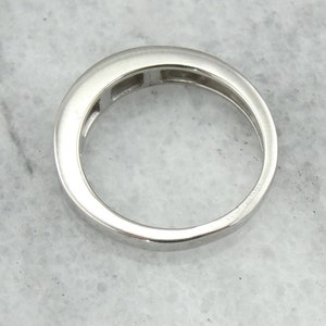 May include: A silver band ring with five small rectangular stones set in a channel setting.