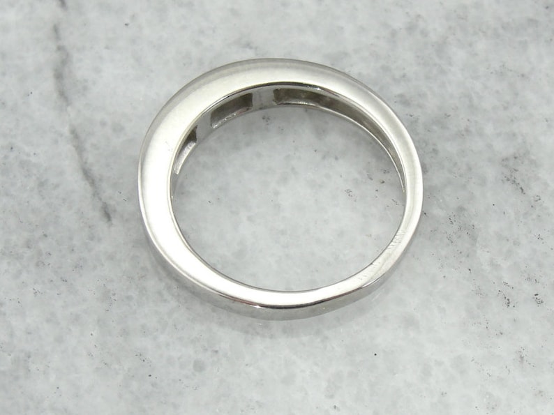 May include: A silver band ring with five small rectangular stones set in a channel setting.