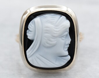 May include: A gold ring featuring a black onyx setting and a white cameo of a woman's profile.