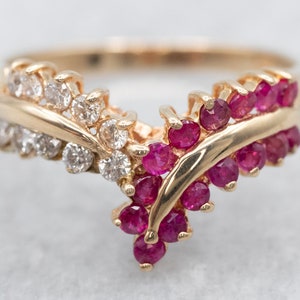 May include: A gold ring with a V-shaped design set with red rubies and white diamonds.