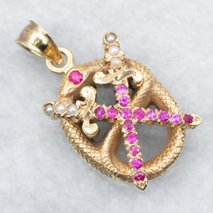 May include: Gold pendant with a snake design and two crossed swords set with pink and white stones.