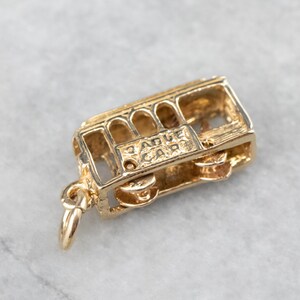 May include: Gold-toned charm in the shape of a San Francisco cable car. The charm has a detailed design and the words "Cable Car" are inscribed on the side.