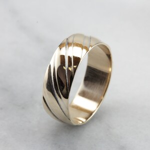 May include: A gold wedding band with a textured, grooved design. The band is polished and has a smooth finish.