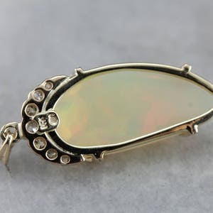May include: A gold pendant featuring a large oval opal with a delicate halo of small round diamonds. The pendant has a bail for attaching to a chain.