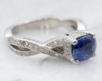 May include: A silver ring with a blue sapphire gemstone and a twisted band accented with small diamonds.