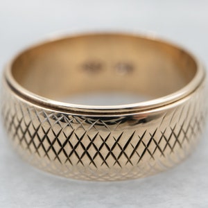 May include: A gold wedding band with a diamond-shaped pattern.