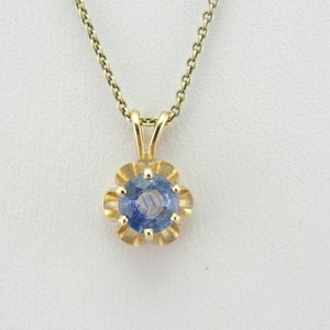 Op de afbeelding: Een delicate gouden ketting met een hanger met een ronde blauwe saffier-steen in een bloemvormig frame.