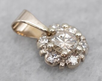 May include: A gold pendant with a round, clear gemstone surrounded by smaller, clear gemstones.