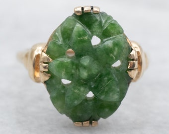 May include: A green jade ring with a carved floral design set in yellow gold.
