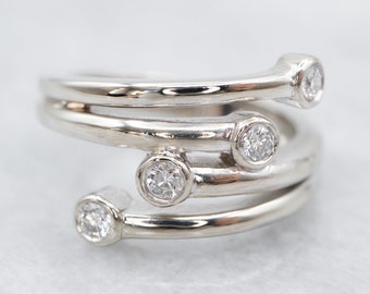 May include: A silver ring with four round diamonds set in the band. The ring is made of multiple bands that are twisted together.