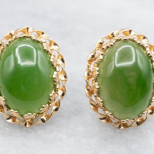 Puede incluir: Un par de pendientes de oro con piedras de jade verde engastadas en un diseño delicado y ornamentado.