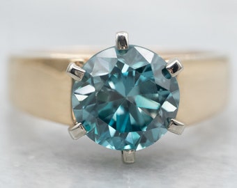 May include: A gold ring with a large, round, blue gemstone set in a six-prong setting.